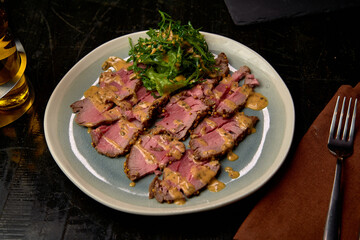 A Delicious Plate of Sliced Grilled Meat Served with Fresh Salad and Savory Sauce, Perfectly Arranged for a Gourmet Dining Experience