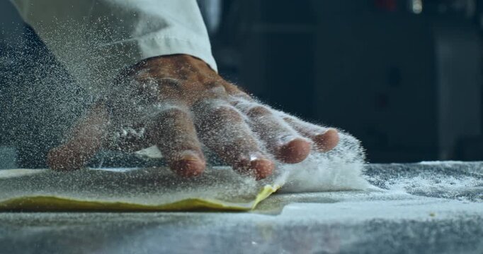 Chef&rsquo;s Hand Pressing Dough with Flying Flour. Slow Motion Close Up of Artisan Cooking Process in Professional Kitchen, Emphasizing Texture, Craftsmanship, and Culinary Tradition at 1000 fps.