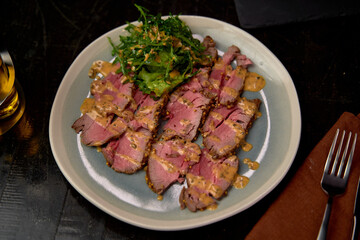 Deliciously Plated Sliced Beef with Nutty Sauce and Fresh Greens Garnish for a Flavorful Culinary Experience