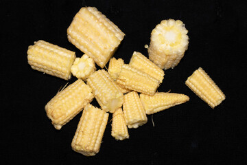 Close up of baby sweetcorn chopped on black background