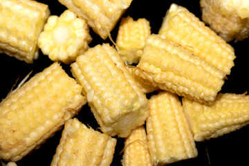 Close up of baby sweetcorn chopped on black background