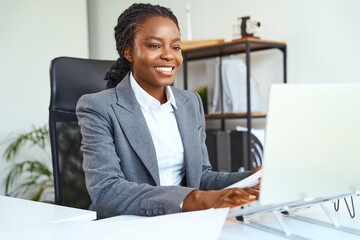 Confident Businesswoman Smiling While Working On Laptop In Modern Office Setting, Focused And...