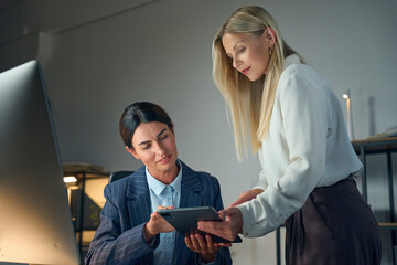 Two Professional Businesswomen Collaborating On A Project Using A Tablet In A Modern Office...