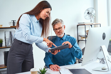 Two Professionals Collaborating In A Modern Office Environment, Analyzing Information On A Tablet....