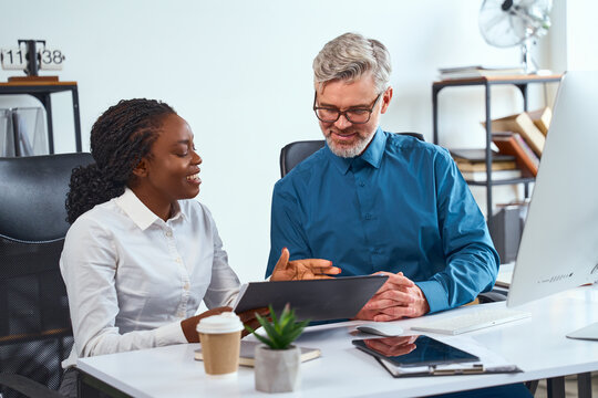 Professional Collaboration Between Business Associates In A Modern Office, Discussing Strategies And Ideas. Represents Teamwork, Creativity, And Multicultural Workplace Dynamics.