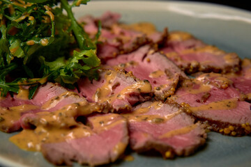 Deliciously Seared Beef Slices Drizzled with Savory Sauce Accompanied by Fresh Leafy Greens on a Gourmet Plate