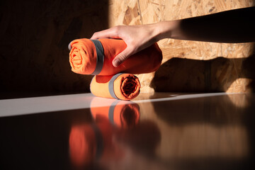 Close-up of a hand taking a rolled orange microfiber hiking towel. Bright outdoor gear for travel, hygiene, and post-shower relaxation