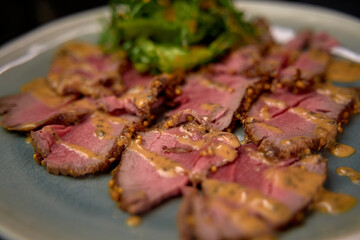 Tender Slices of Roast Beef Served with Flavorful Mustard Sauce and Fresh Greens on a Plate, Perfectly Cooked and Plated for Culinary Delight