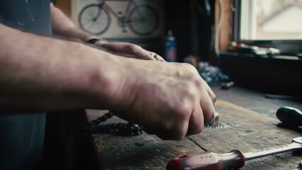 Skilled hands meticulously assemble a bicycle chain on a weathered workbench, showcasing detailed craftsmanship and mechanical expertise.