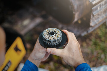 Professional mechanic man holding piston of the hydraulic pump to inspection and repair maintenance heavy machinery Close-up. Compliance and integrity control of the new spare part.