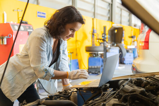 Small business, garage, mechanic, woman, Female owner manages auto maintenance shop using technology to inspect vehicle repair, balancing work with technology, professional car service, customer care