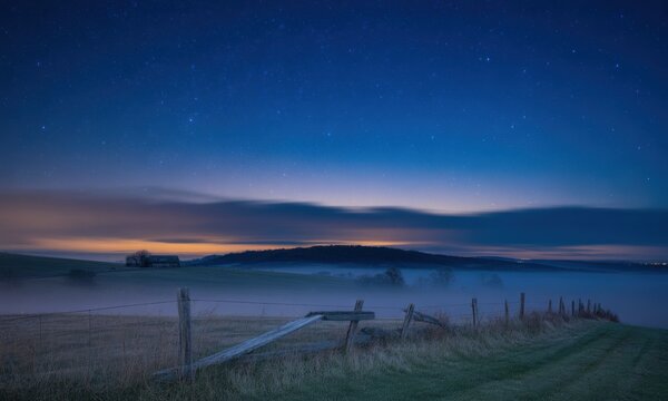 Misty, starry night over a field with a rustic wooden fence - Powered by Adobe