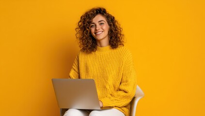 Smiling woman with curly hair works on her laptop in a bright yellow setting, radiating positivity and productivity.