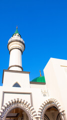 Obraz premium Islamic Mosque Minaret with Green Dome and Loudspeakers under Clear Blue Sky