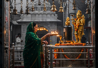 Devoted Woman in Dark Green Georgette Saree Performing Aarti Before Golden Shiva Idol