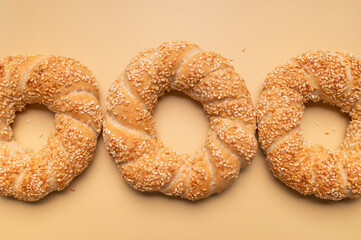 Simit or gevrek, round bagel with sesame seeds on beige background top view. Creative layout with food. Traditional Turkish pastry. Delicious fresh homemade pastry, bakery product. Bagel mockup