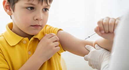 Young boy receives injection in arm, showing apprehension He wears yellow shirt The image conveys healthcare, vaccination, and childhood immunization