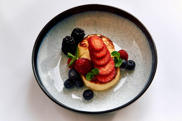 A Colorful Culinary Delight Featuring a Delicious Dessert of Fluffy Cake, Fresh Berries, and Garnishing Mint Leaves in a Beautiful Bowl Setting