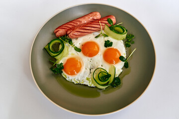 A Morning Plate Featuring Perfectly Cooked Fried Eggs Surrounded by Sausages and Fresh Vegetables for a Nutritious Breakfast