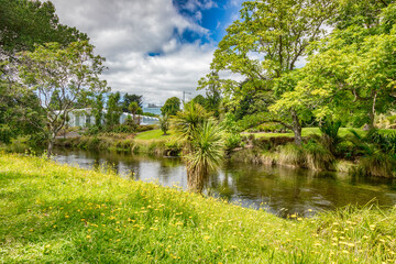 Christchurch, New Zealand - The Avon River meanders through Christchurch Botanic Gardens and Hagley Park, with wildflowers in the foreground, Visitor Centre can be seen across the river.