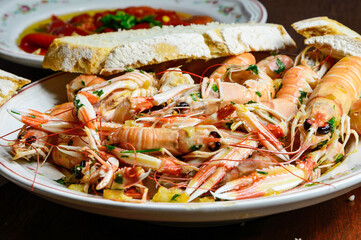 Cigalas pequeñas salteadas con ajo y perejil y pan de payes o antiguo 