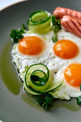 Deliciously Crafted Breakfast Plate Featuring Three Sunny-Side Up Eggs Surrounded by Fresh Greens and Cucumber Twists for a Vibrant Morning Meal