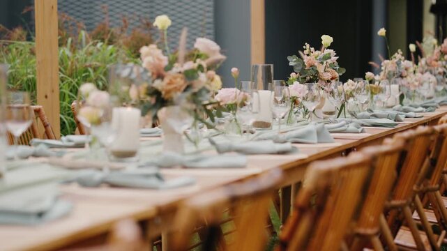 Elegant outdoor dining table set with pastel floral arrangements, candles, and rattan decor&mdash;perfect for a rustic or garden wedding reception.