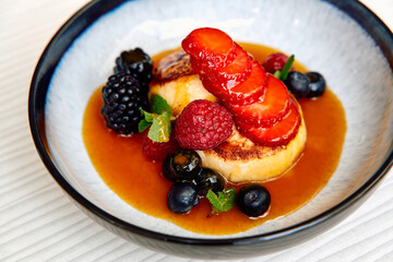Deliciously Plated Dessert Featuring Grilled Custard, Fresh Berries, and a Glaze of Caramel; A Colorful and Tempting Treat for Any Sweet Tooth.