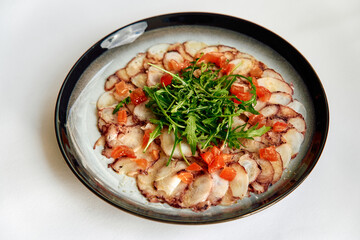 Deliciously Crafted Carpaccio with Fresh Ingredients, Featuring Tantalizing Slices of Tender Meat Garnished with Vibrant Greens and Juicy Tomatoes