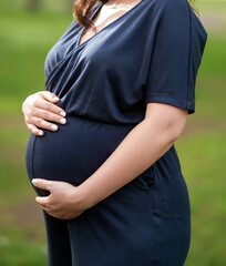 Pregnant woman outdoor stands selective focus