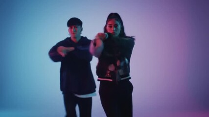 a man and a woman—dancing hip hop as a dynamic duo against a vibrant, color-changing neon background. Energetic movements and synchronized pair choreography capture the modern vibe of a teen dance sch