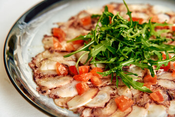 A Delicious Plate of Freshly Prepared Carpaccio Topped with Arugula and Diced Tomatoes Perfectly Arranged for a Tasteful Presentation