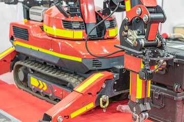 Large red industrial robot in a workshop, equipped with attachments like a circular saw, drill, and articulated arms Located in an industrial environment with concrete flooring, strong artificial li