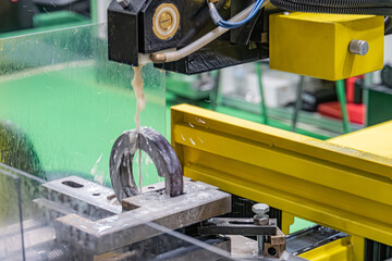 Image depicts an industrial scene with a robotic arm placing a metallic ring onto a larger plate...