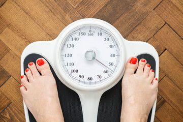 Top view of feet on scale with wooden floor
