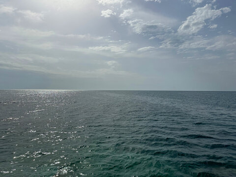 Open sea glittering waters and cloudy sky.