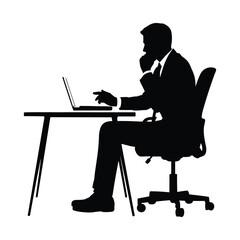 Silhouette of a businessman working on a laptop at a desk
