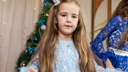 Little girls in festive dress dancing near christmas tree at home