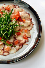 Deliciously Crafted Carpaccio Garnished with Fresh Arugula and Tomato, Showcasing the Art of Culinary Presentation and Flavor Balance in Italian Cuisine
