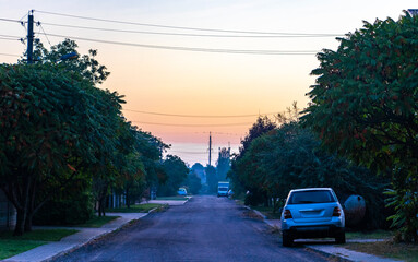 Colorful sunset village city street with cars and houses Belarus.