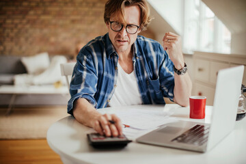 Mature man calculating and going over his bills and home finances