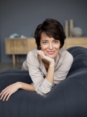 Obraz premium Relaxing woman posing on a couch in a modern living room lifestyle photography indoor warm atmosphere