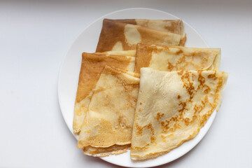 Traditional Russian and Estonian pancakes (blini) folded on a white plate. Perfect for stock photography focused on homemade food, Eastern European cuisine, breakfast concepts, or minimalist meals.