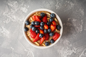 Oatmeal with ripe strawberries, blueberries and honey in the bowl. Selective focus.