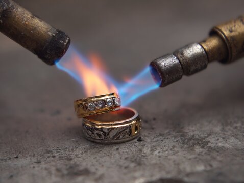 Two jeweler's torches heating gold rings