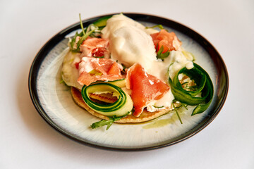 Deliciously Crafted Dish Featuring Fresh Salmon, Creamy Sauce, and Garnished with Cucumber and Herbs on a Round Plate