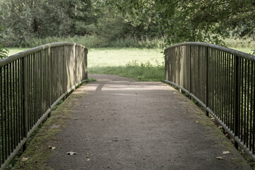 Obraz premium Small metal bridge crossing over dry creek in summer park