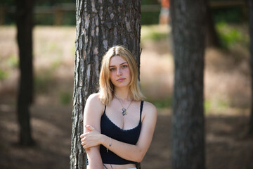A young, beautiful blonde woman dressed in white trousers and a black cotton shirt leans her back...