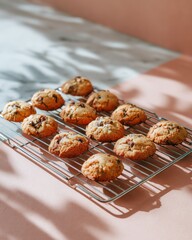 Cooling rack with fresh baked cookies, light shadows, soft pastel backdrop, home baking atmosphere