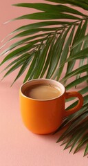 Orange mug of coffee beside a palm frond on a blush-pink background